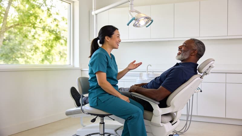 Illustrative image — a dental hygienist and a patient laughing together in a bright treatment room