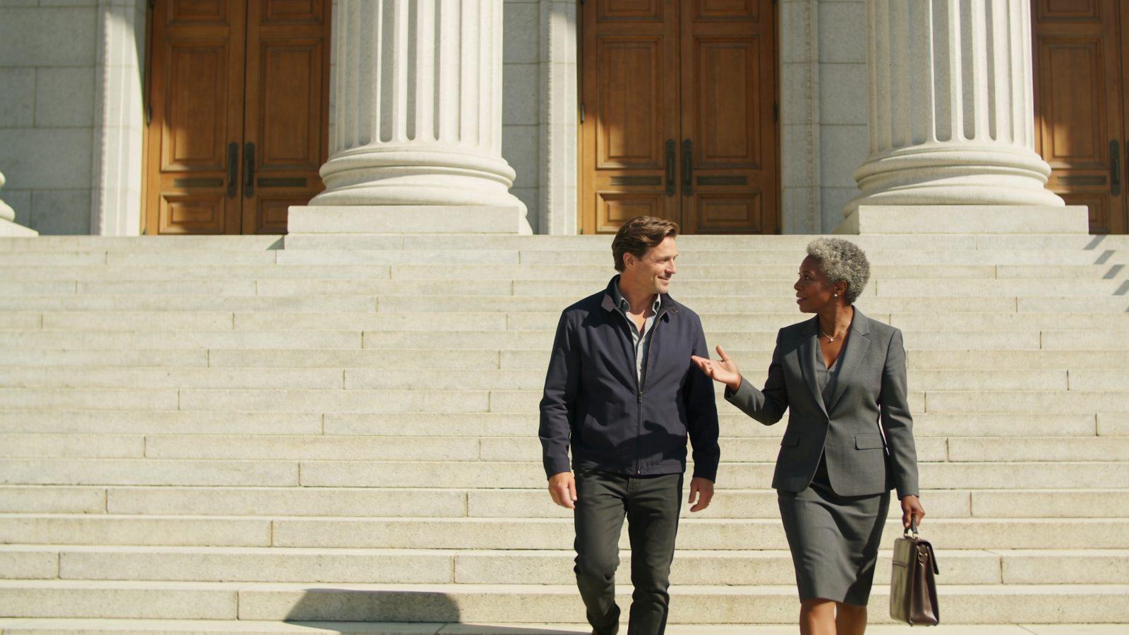 Illustrative image — a lawyer and her client talking as they walk down the stone steps of a courthouse